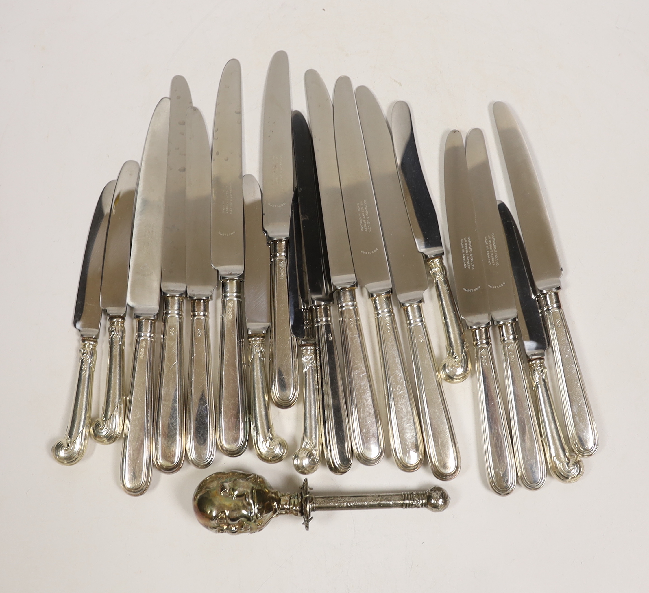 A set of six modern silver handled dessert knives and six table knives, Garrard & Co Sheffield, 1974, a set of six silver pistol handled tea knives and a silver plated 'Humpty Dumpty' child's rattle(a.f.).